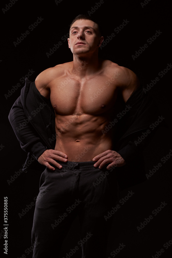 Naklejka premium Bodybuilder standing in black hoodie. Studio shot. Isolated