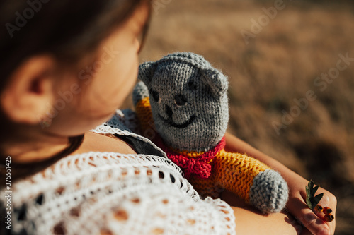 Fototapeta Naklejka Na Ścianę i Meble -  Close up cute little child with a knitted toy in hand in nature. Close-up portrait.