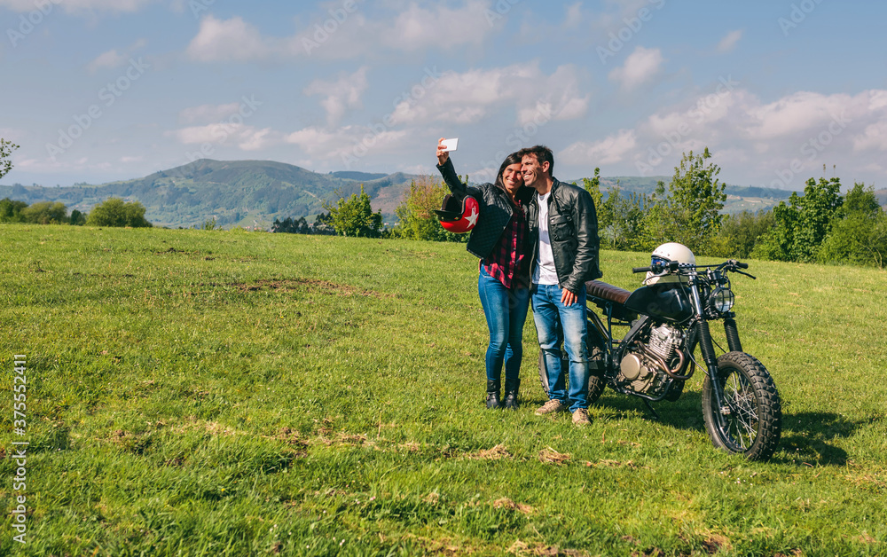Young couple taking a selfie with a motorcycle outdoors