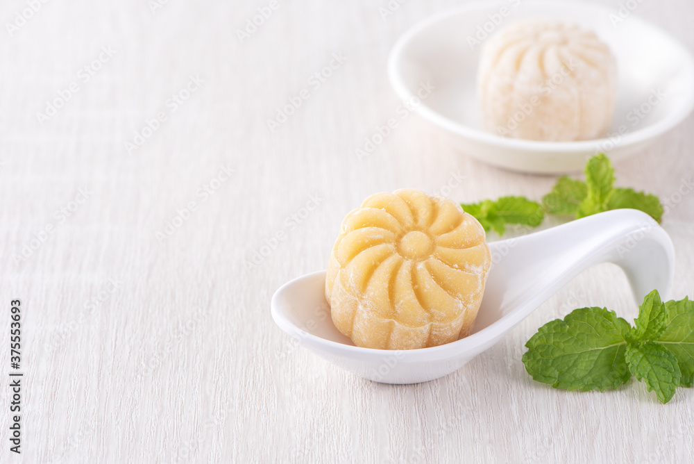 Colorful snow skin moon cake, sweet snowy mooncake, traditional savory dessert for Mid-Autumn Festival on bright wooden background, close up, lifestyle. Colorful snow skin moon cake, sweet snowy mooncake, traditional savory dessert for Mid-Autumn Festival on bright wooden background, close up, lifestyle.