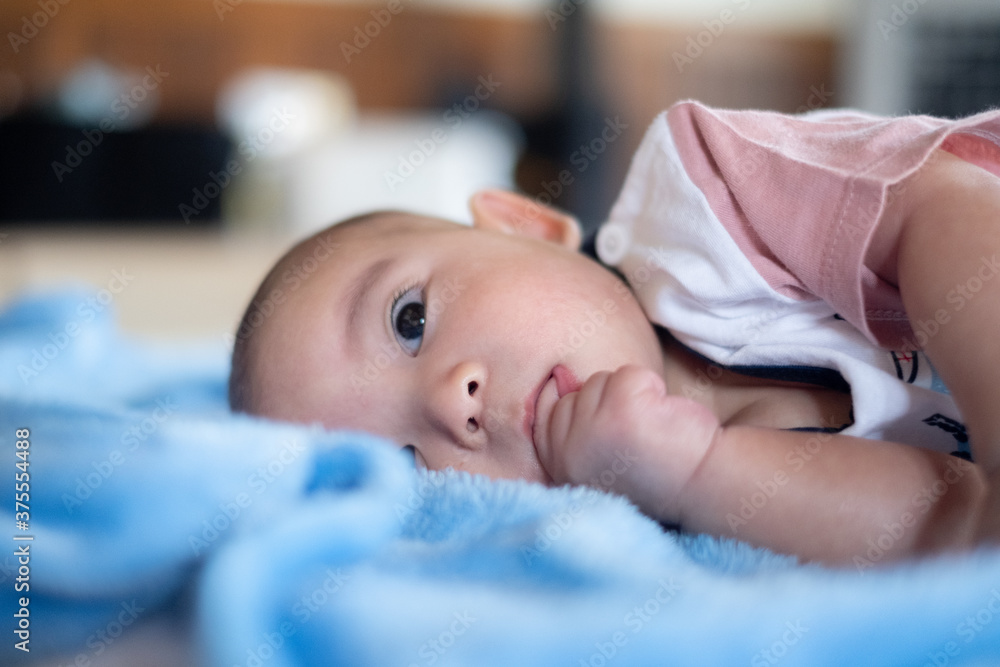 Asian Adorable infant baby lying on bed with toy Music Ball. Baby Child early development and activity Tummy time fun Asian Adorable infant baby lying on bed with toy Music Ball. Baby Child early development and activity Tummy time fun