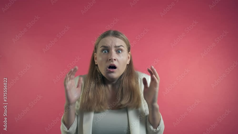 The frightened girl is surprised and agrees to the terms of the person who attacked her. Fear of war, pandemic, terrible events. Pink background. The frightened girl is surprised and agrees to the terms of the person who attacked her. Fear of war, pandemic, terrible events. Pink background.