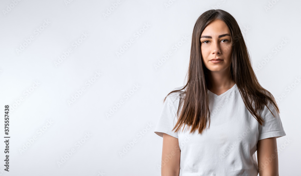 Modern girl with long chestnut hairs in casual light clothes posing isolated on white wall background. Copy space Modern girl with long chestnut hairs in casual light clothes posing isolated on white wall background. Copy space