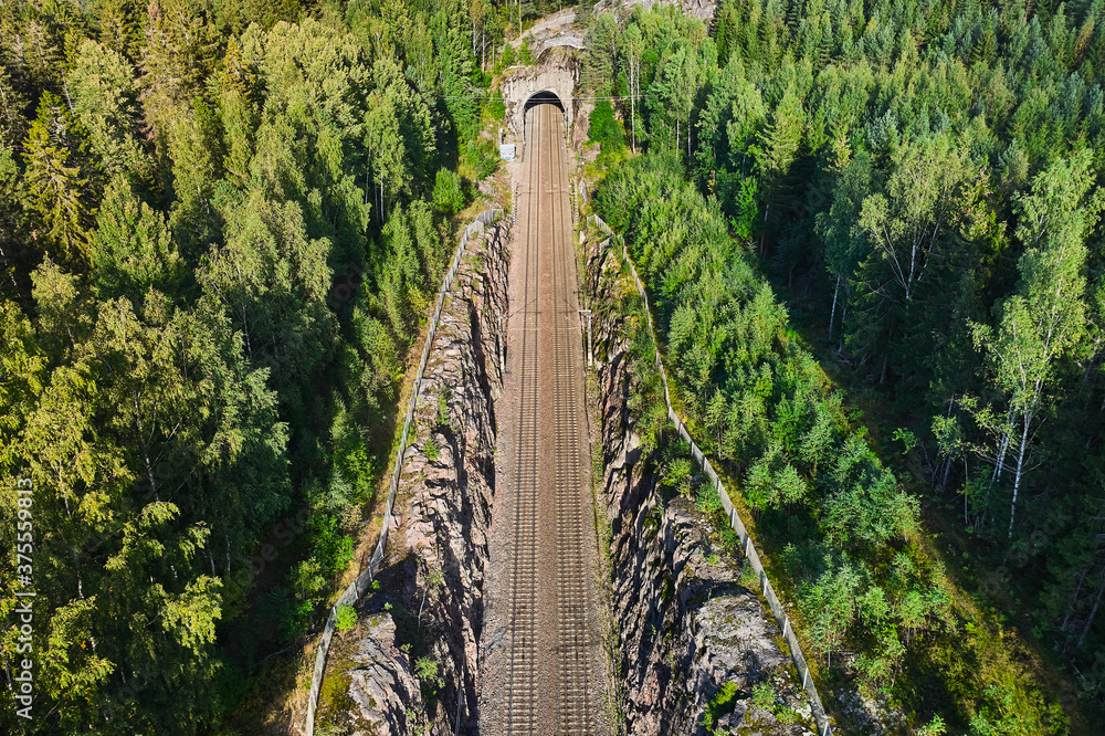 Aerial view of the railway track. The railroad between the hills goes into a tunnel.