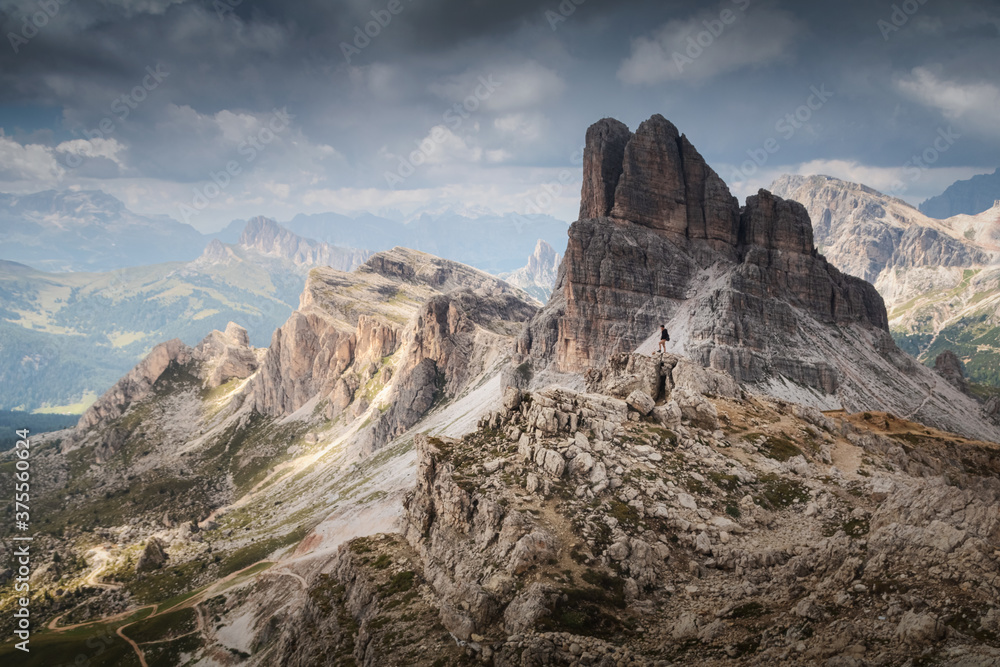Dramatic view in dolomites on the peak Averau with man looking to the valley