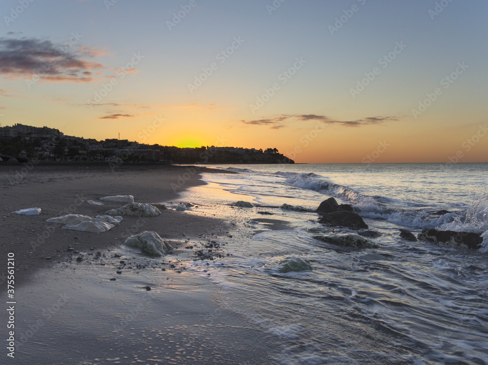Sunrise at the beach with waves and rocks
