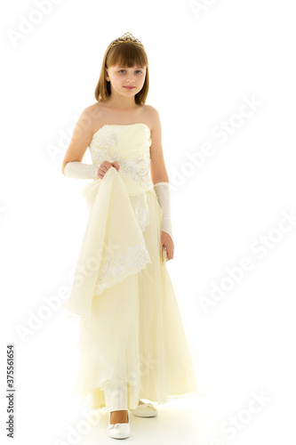 A little girl in a long, elegant dress of a princess. © lotosfoto