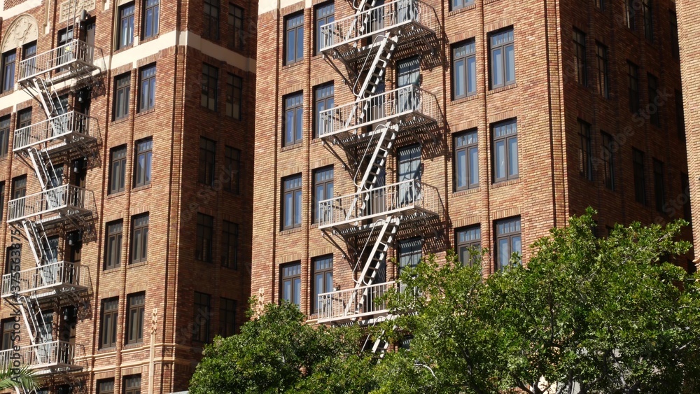Fire escape ladder outside residential brick building in San Diego city, USA. Typical New York style emergency exit for safe evacuation. Classic retro house exterior as symbol of real estate property
