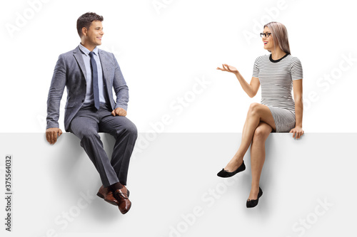 Blond woman sitting on a blank panel and talking to a man in a suit