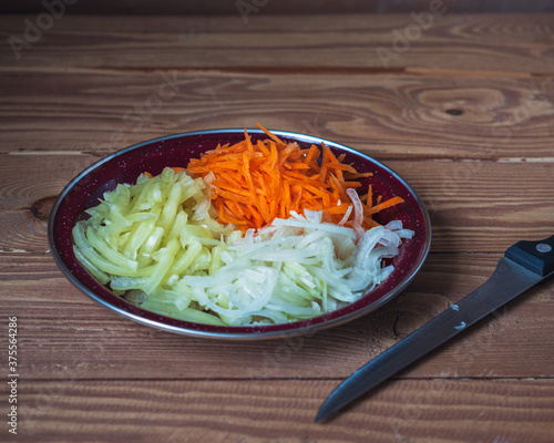 Set of chopped vegetables for cooking, salads close-up and table knife on a table