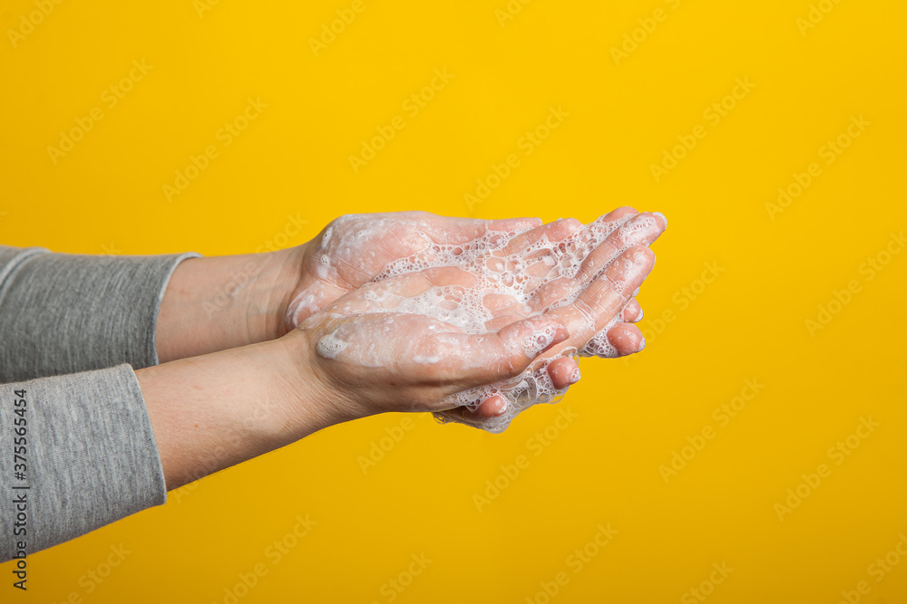 washable hands close-up on a yellow studio background. Proper hand washing as a prevention of viruses .