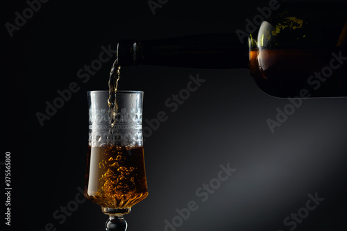 Фототапет Aged golden fortified wine from the vintage bottle being poured into a crystal glass