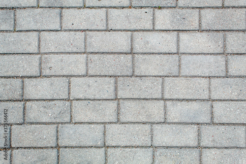 road paved with sidewalk tiles. texture of light gray bricks.