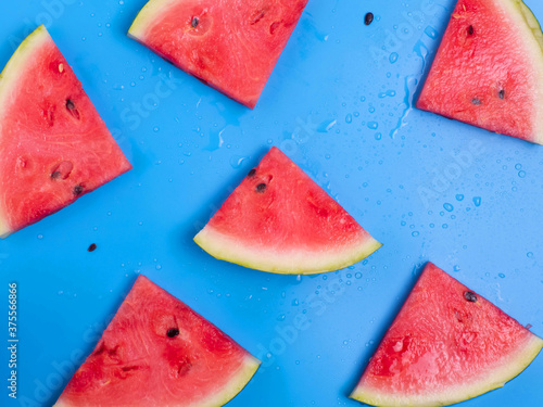 Creative flatley top view of fresh watermelon slices on a blue background.