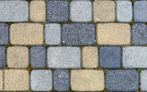 road paved with sidewalk tiles. texture of yellow  light and dark gray bricks.