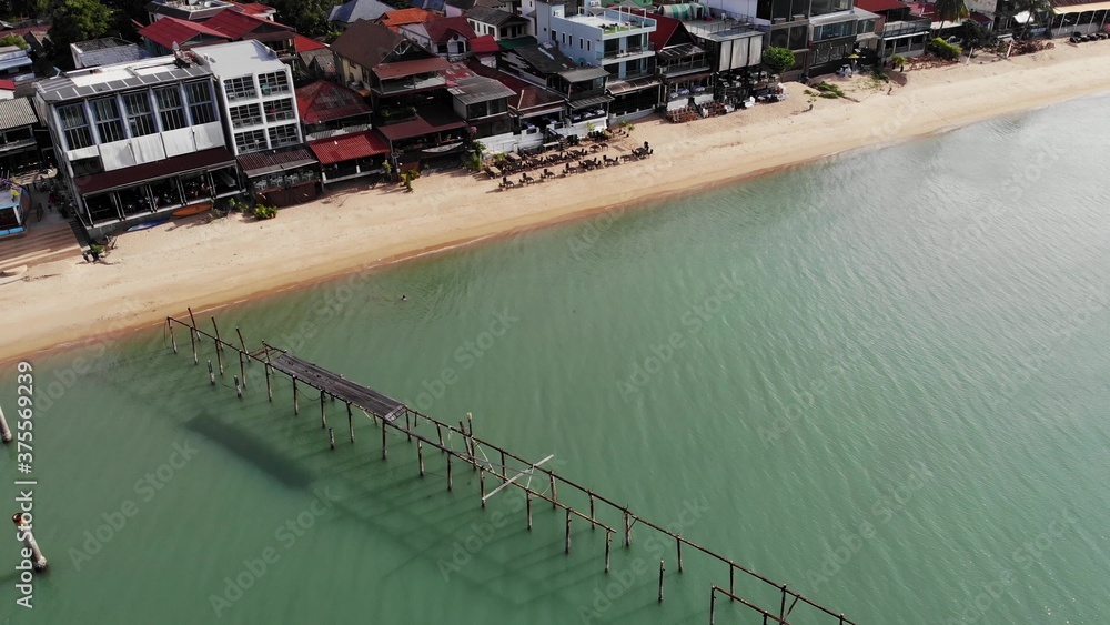 Fisherman village on seashore. Aerial view of typical touristic place on Ko Samui island with souvenir shops and walking street on sunny day. Architecture in asia, local settlement drone view