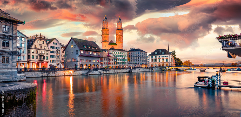 Colorful evening view of Grossmunster Church. Great autumn cityscape of Zurich, Switzerland, Europe. Sunset on Limmat River. Traveling concept background.
