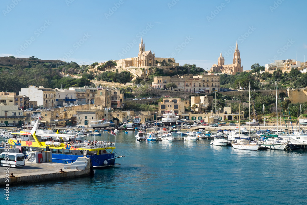 The ferry from Malta to Gozo island goes to the picturesque harbor of Mgarr port where the luxury yachts and traditional fishing boats are staying