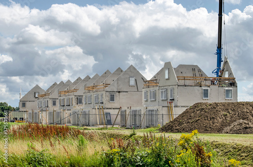 Numansdorp, The Netherlands, July 10, 2020: construction site of a row of terrace houses, with prefab concrete walls awaiting finishing under a dramatic sky