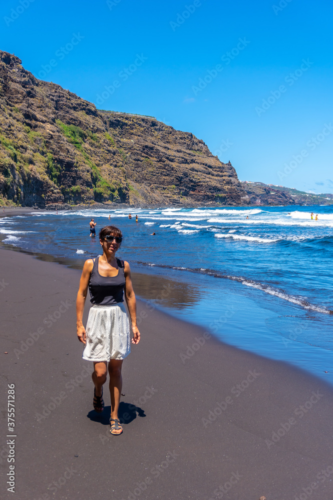 A young woman walking in summer by the sea in Playa de Nogales in the east of the Island of La Plama, Canary Islands. Spain