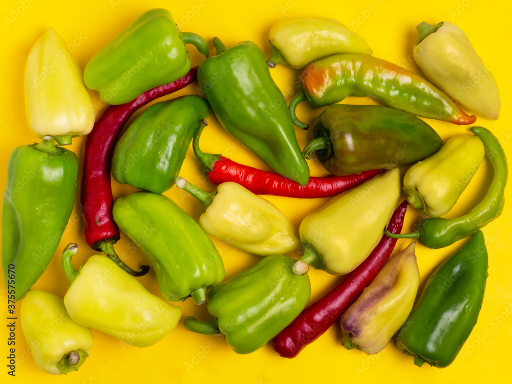 Sweet and hot pepper on a yellow background. A large number of peppers in the pile. Sweet and hot pepper on a yellow background. A large number of peppers in the pile.