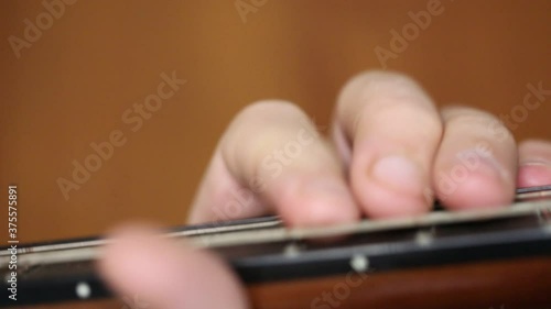 playing the guitar brown close-up fingers busting the strings