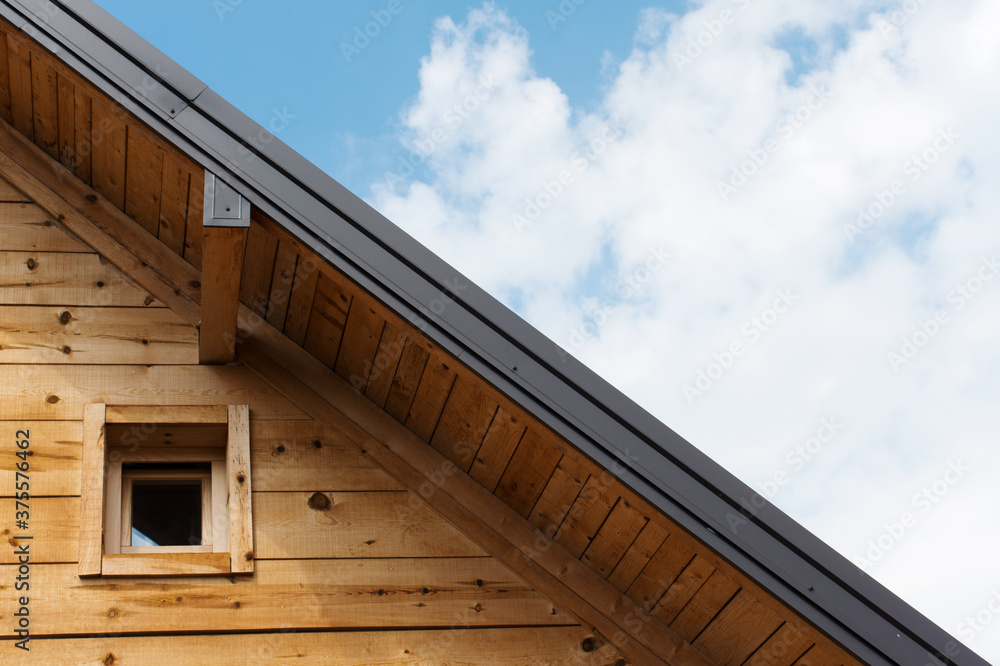 Apartment window on a wooden surface and bright sky above. House roof and window isolated.