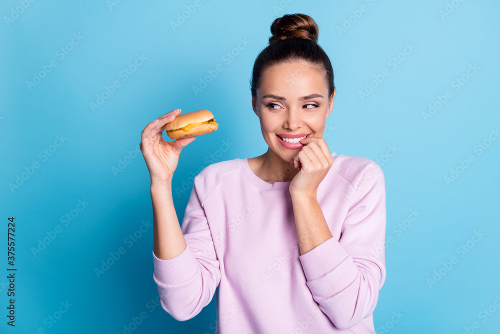 Photo of dreamy hungry girl touch finger teeth want eat hamburger wear violet sweater isolated over blue color background Photo of dreamy hungry girl touch finger teeth want eat hamburger wear violet sweater isolated over blue color background
