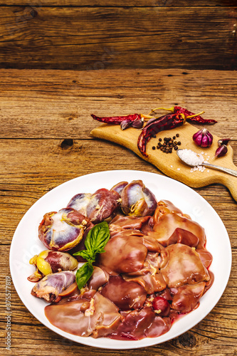 Fresh raw chicken offal: heart, liver, stomach with dry spices, sea salt, chili pepper on wooden table photo