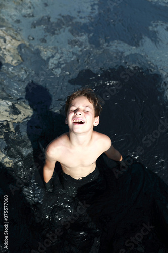 Child sitting in mud © Arkady Chubykin