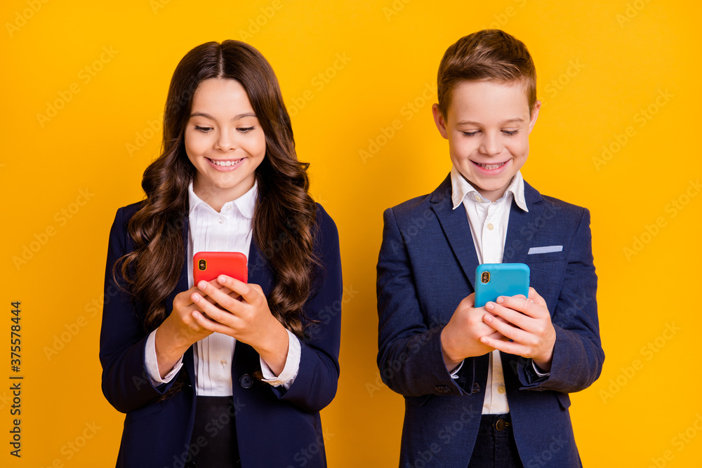 Portrait of his he her she attractive focused cheery addicted small little schoolkids using gadget device chatting web service blog isolated bright vivid shine vibrant yellow color background Portrait of his he her she attractive focused cheery addicted small little schoolkids using gadget device chatting web service blog isolated bright vivid shine vibrant yellow color background