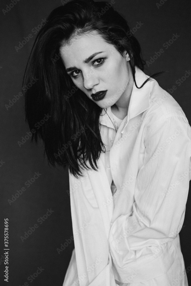 fashion portrait of attractive brunette girl posing in white shirt. Black and white with added noise
