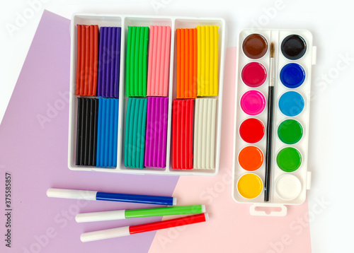 Stationery top view. Watercolor in a box, felt-tip pens, plasticine. Multicolored.