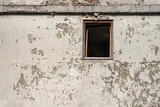Kaputtes Fenster ohne Scheibe in einer alten weißen Hauswand