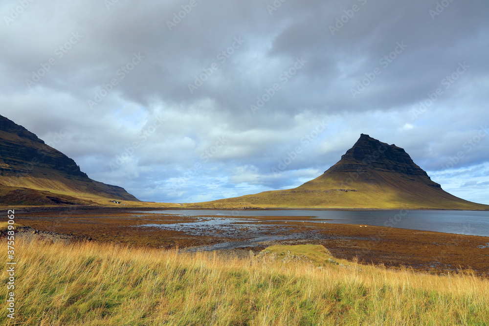 Stunning and famous Kirjkufell arrowhead mountain with blue sky and clouds in background. Daytime shot on Snaefellsnes peninsula, Iceland