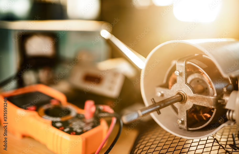 Close-up of iron motor from home cooling fan lies on a table under repair Close-up of iron motor from home cooling fan lies on a table under repair