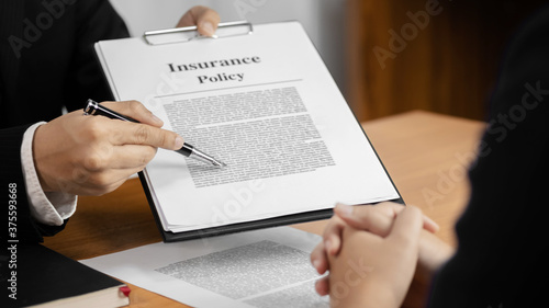 Insurance agent with client and sign contract insurance policy.