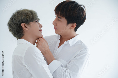 Asian attractive LGBT young gay couple hugging looking each other and kissing in room on white background