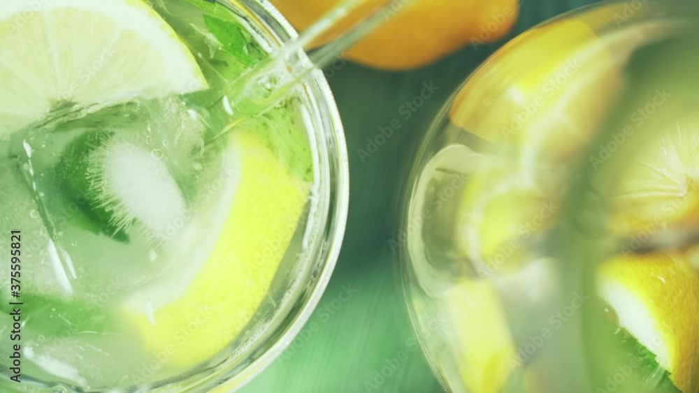 Hand puts ice cubes with tongs into a glass of fresh lemonade. Delicious lemon cocktail, close-up. Hand puts ice cubes with tongs into a glass of fresh lemonade. Delicious lemon cocktail, close-up.