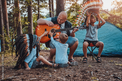 Boys with indiad traditional headwear having a good time with their daddy in the american forest. photo