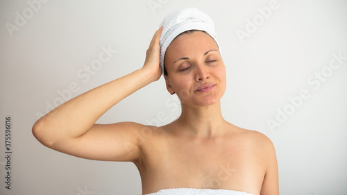 Beautiful woman with her eyes closed and her head and body wrapped in fresh white towels at a spa against a white background .
