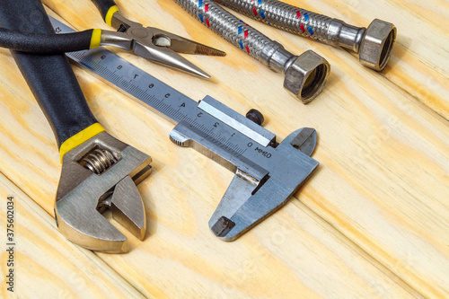 Set of tools and hose for plumbers on wooden boards with space for advertising