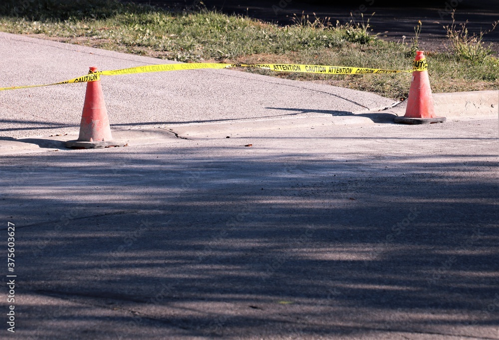 Caution tape and traffic cones spanning the end of a driveway in urban ...