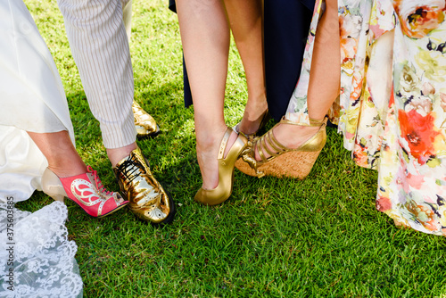 Φωτογραφία Bride, bridesmaids, bridegroom and groomsmen show off their shoes at wedding party celebration on summer green grass outdoors background