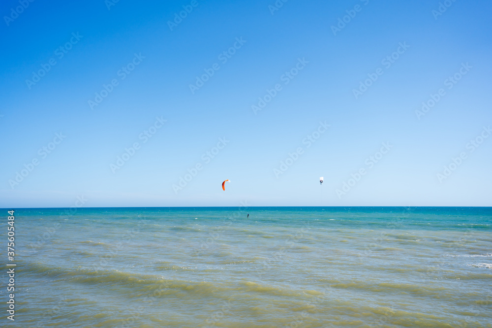 Kite surfing on blue sky ocean waves outdoors background.