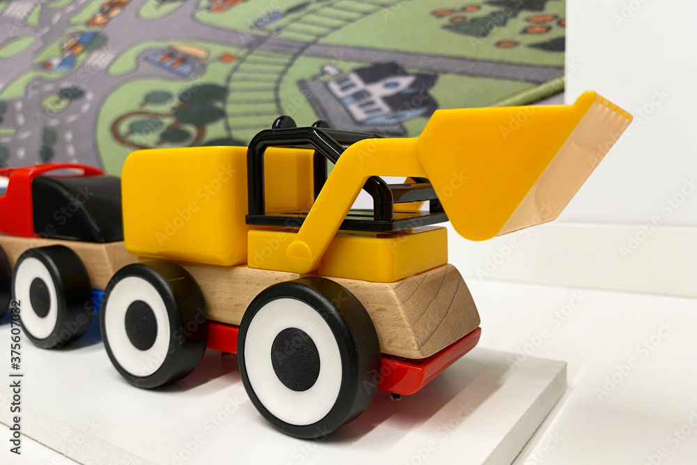 yellow and red toy car bulldozer with a bucket made of plastic and wood stands on a white surface yellow and red toy car bulldozer with a bucket made of plastic and wood stands on a white surface