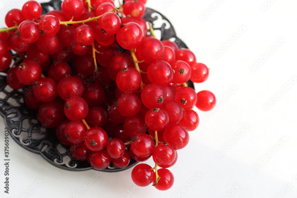 Fresh red currants in plate on white background. Red currants close up.