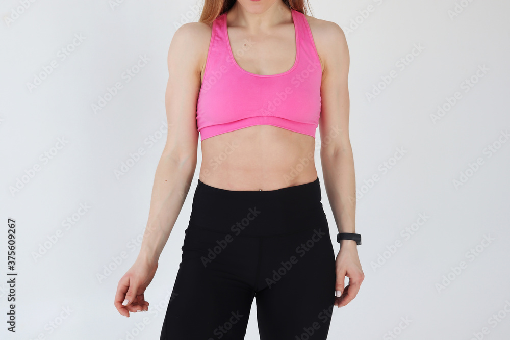 The athletic body of a girl in sportswear. Sporty girl close-up on a white background. The athletic body of a girl in sportswear. Sporty girl close-up on a white background.