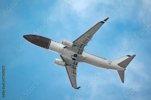 Flying airplane. Commercial passenger jet airliner in flight on bright blue sky with clouds background. Modern technology in fast transportation, business travel, charter tourism, aviation concept.