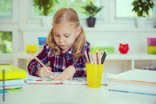 Portrait of pretty school girl are studying at classroom at the table